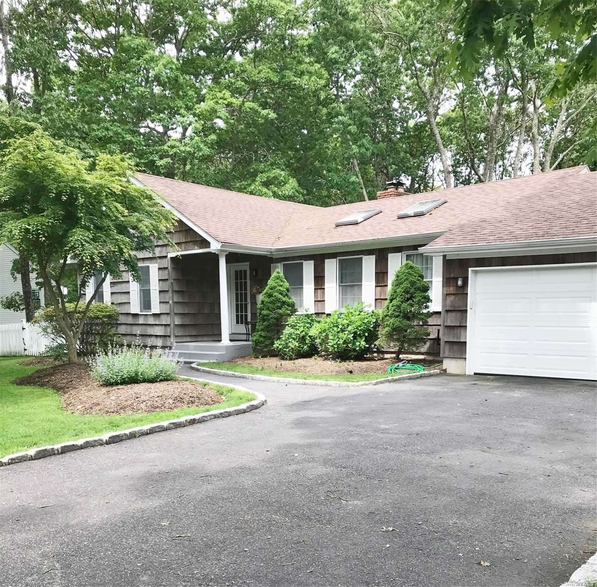 a front view of a house with a garden and trees