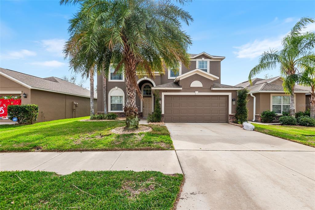 a front view of a house with a garden and palm trees