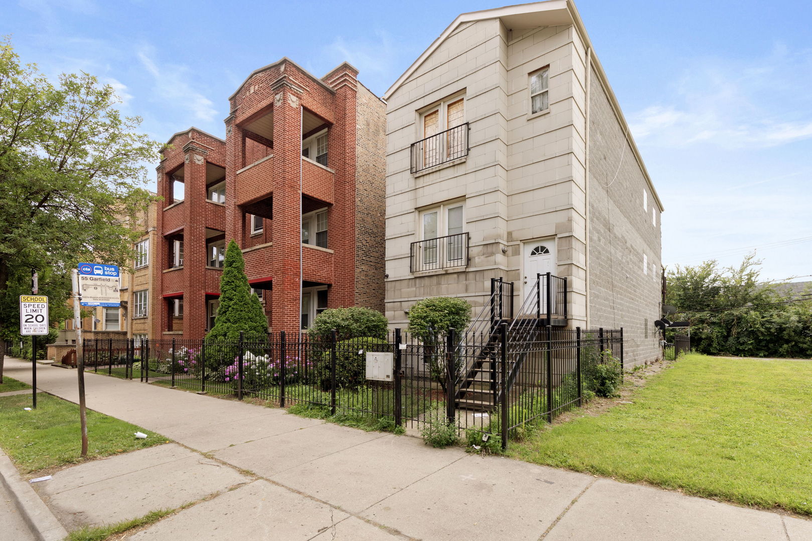 a front view of a multi story residential apartment building with yard and retail shops