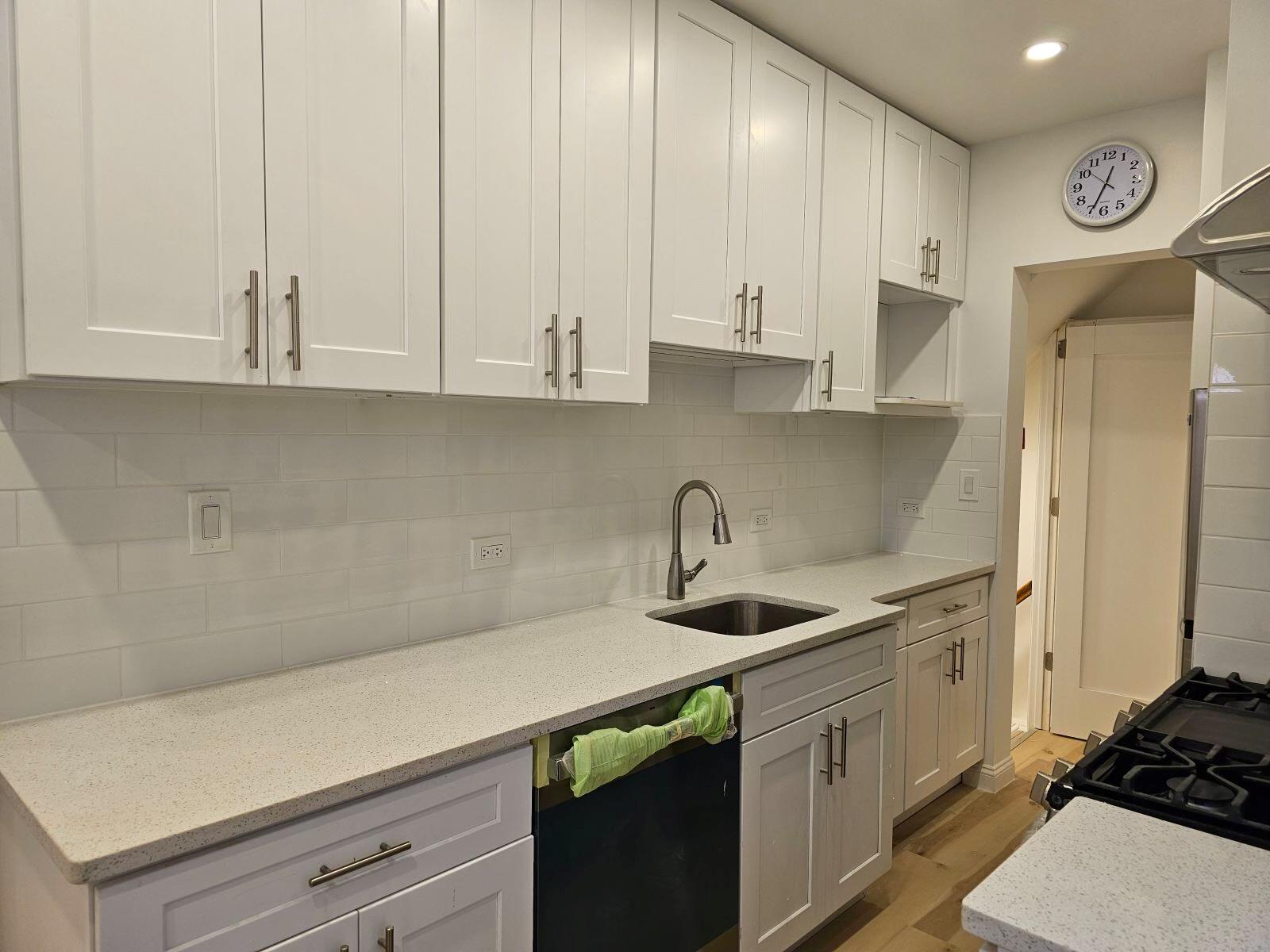 Kitchen featuring white cabinetry, sink, black dishwasher, and light wood-type flooring