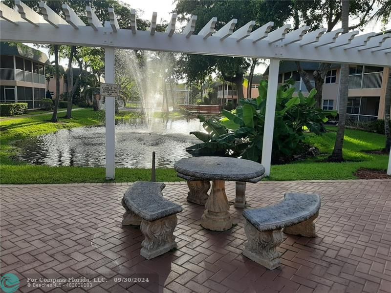 a view of a backyard with table and chairs potted plants and a palm tree