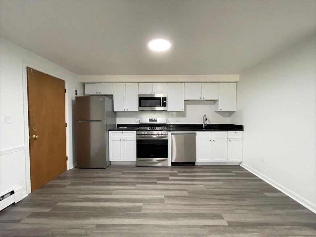 a kitchen with granite countertop a refrigerator and a stove top oven