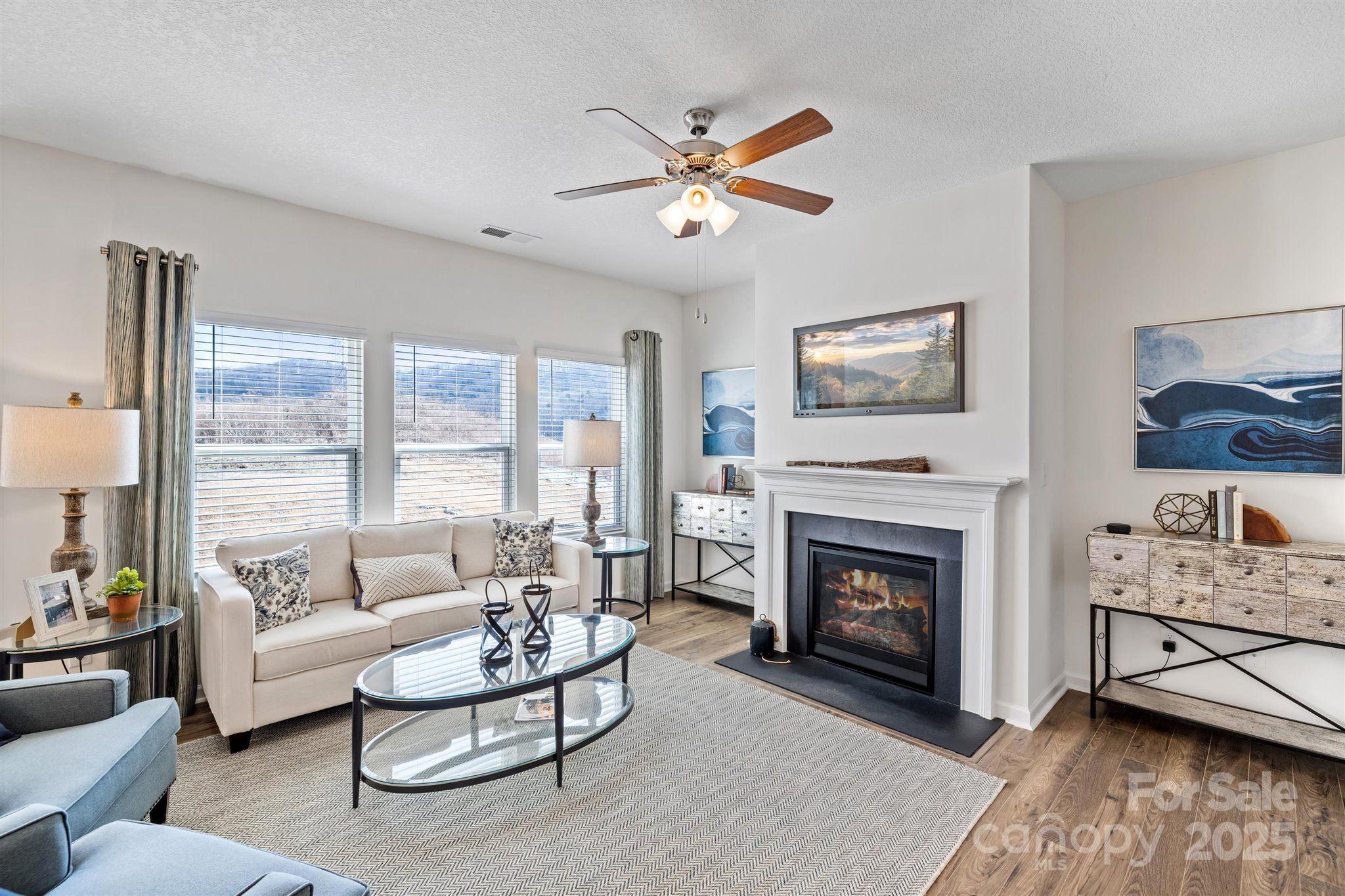 a living room with furniture a fireplace and a large window