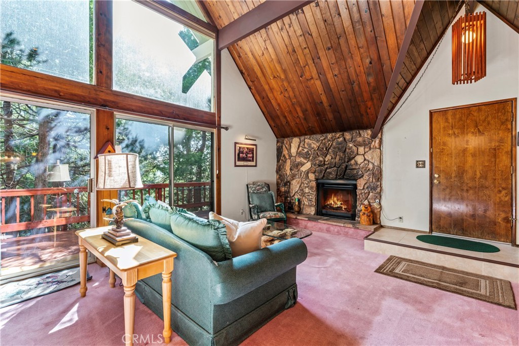 a living room with furniture a fireplace and a floor to ceiling window