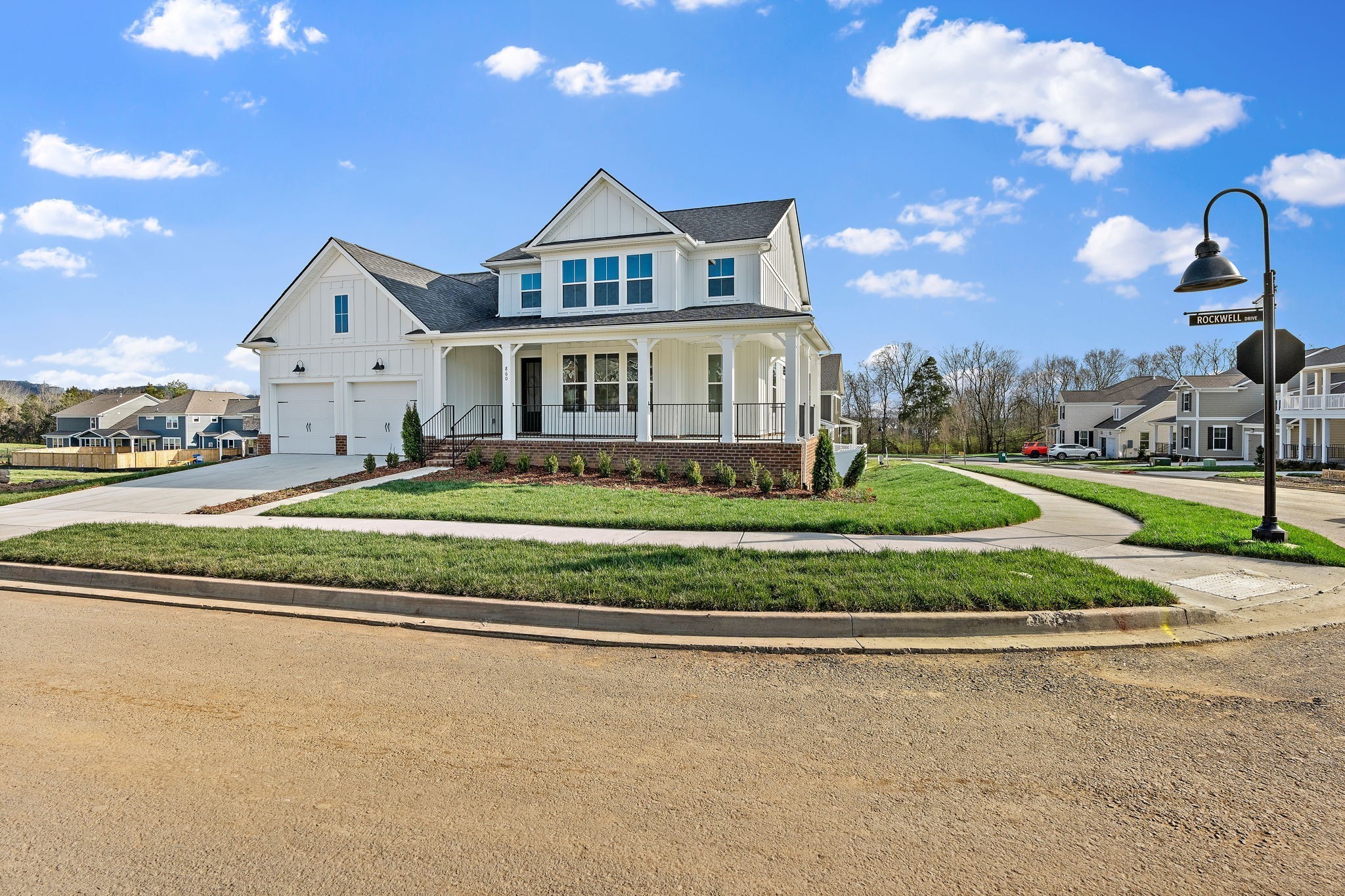 a view of a house next to a big yard with plants and large tree