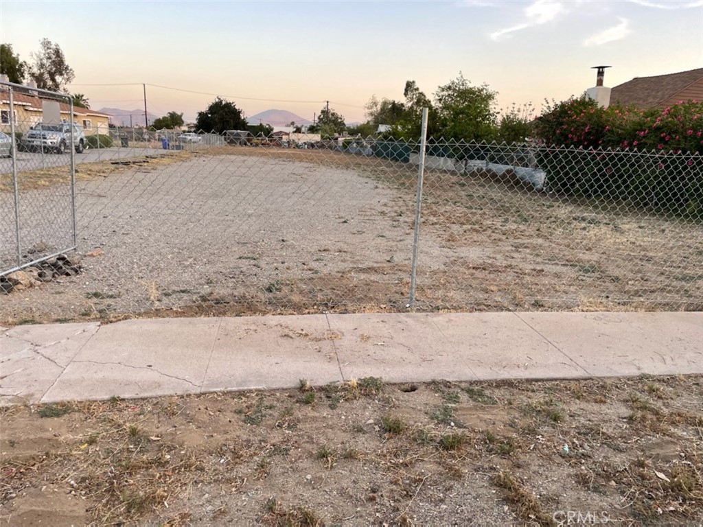 a view of a dry yard with wooden fence