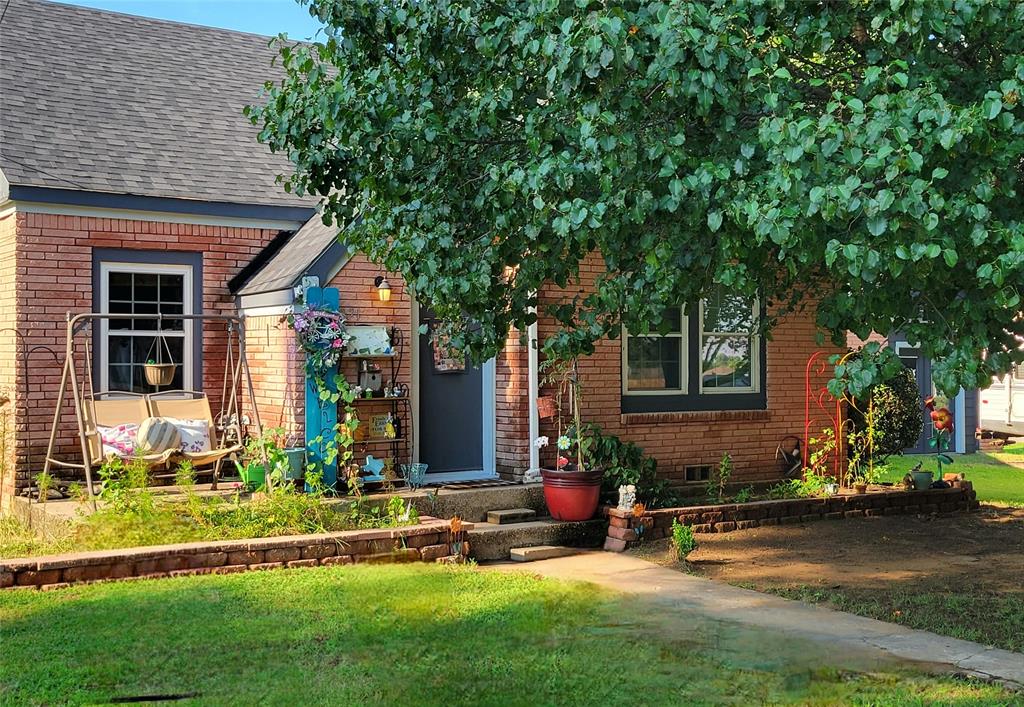 a front view of a house with a yard and table and chairs in porch