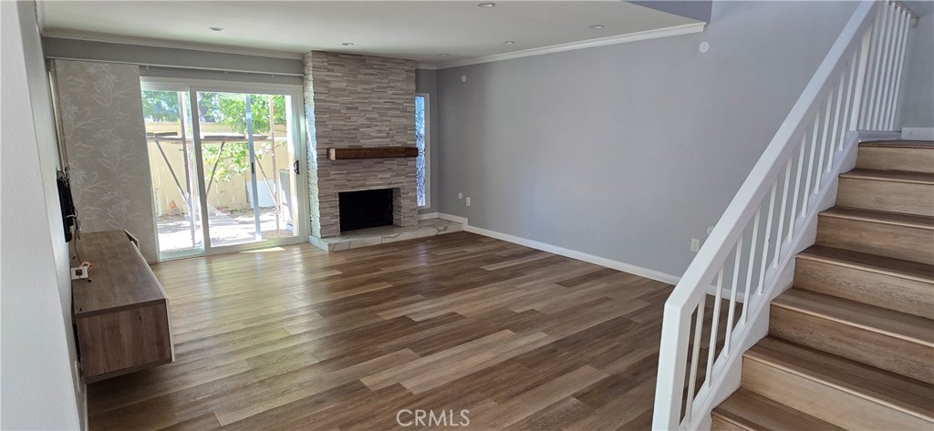 a view of a livingroom with wooden floor fireplace and a window