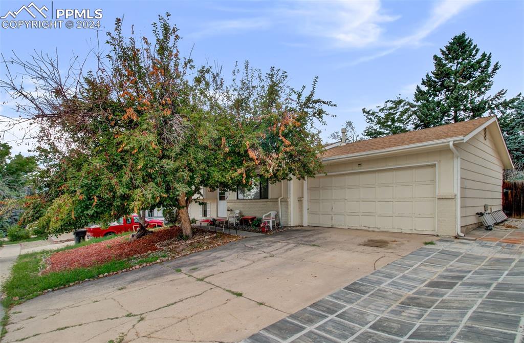 View of property hidden behind natural elements featuring a garage