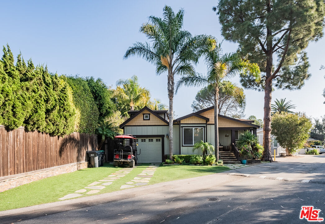 a front view of a house with a garden and trees