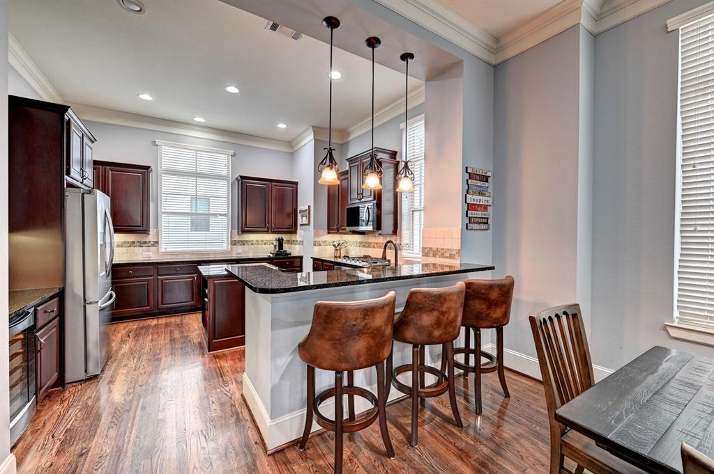 a kitchen with stainless steel appliances granite countertop a kitchen island hardwood floor sink stove dining table and chairs