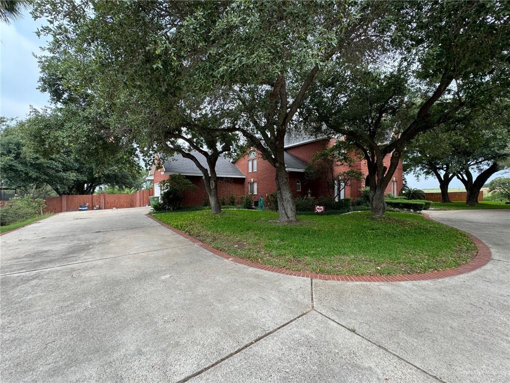 a view of a white house with a big yard and large trees