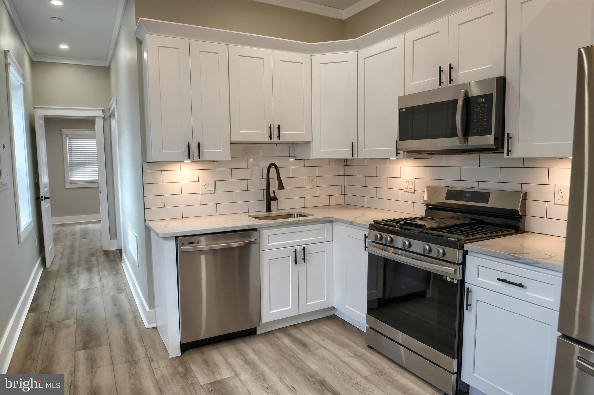 a kitchen with stainless steel appliances white cabinets and a stove top oven