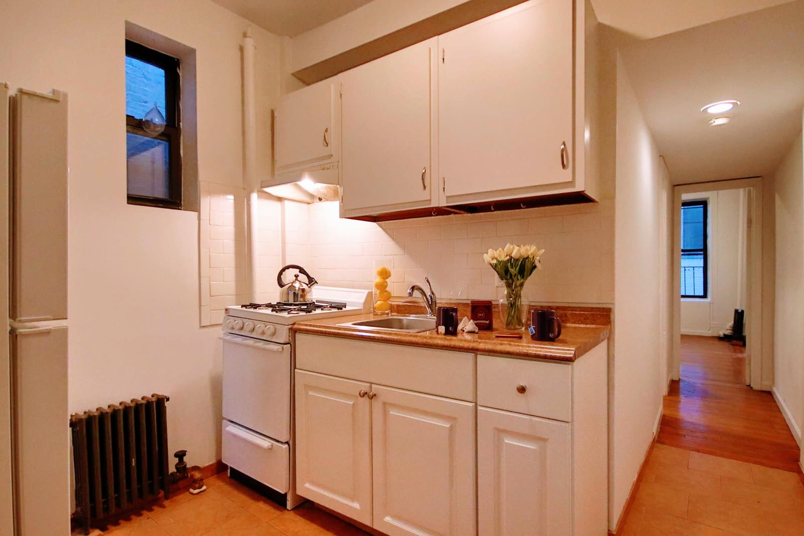 a kitchen with white cabinets and sink