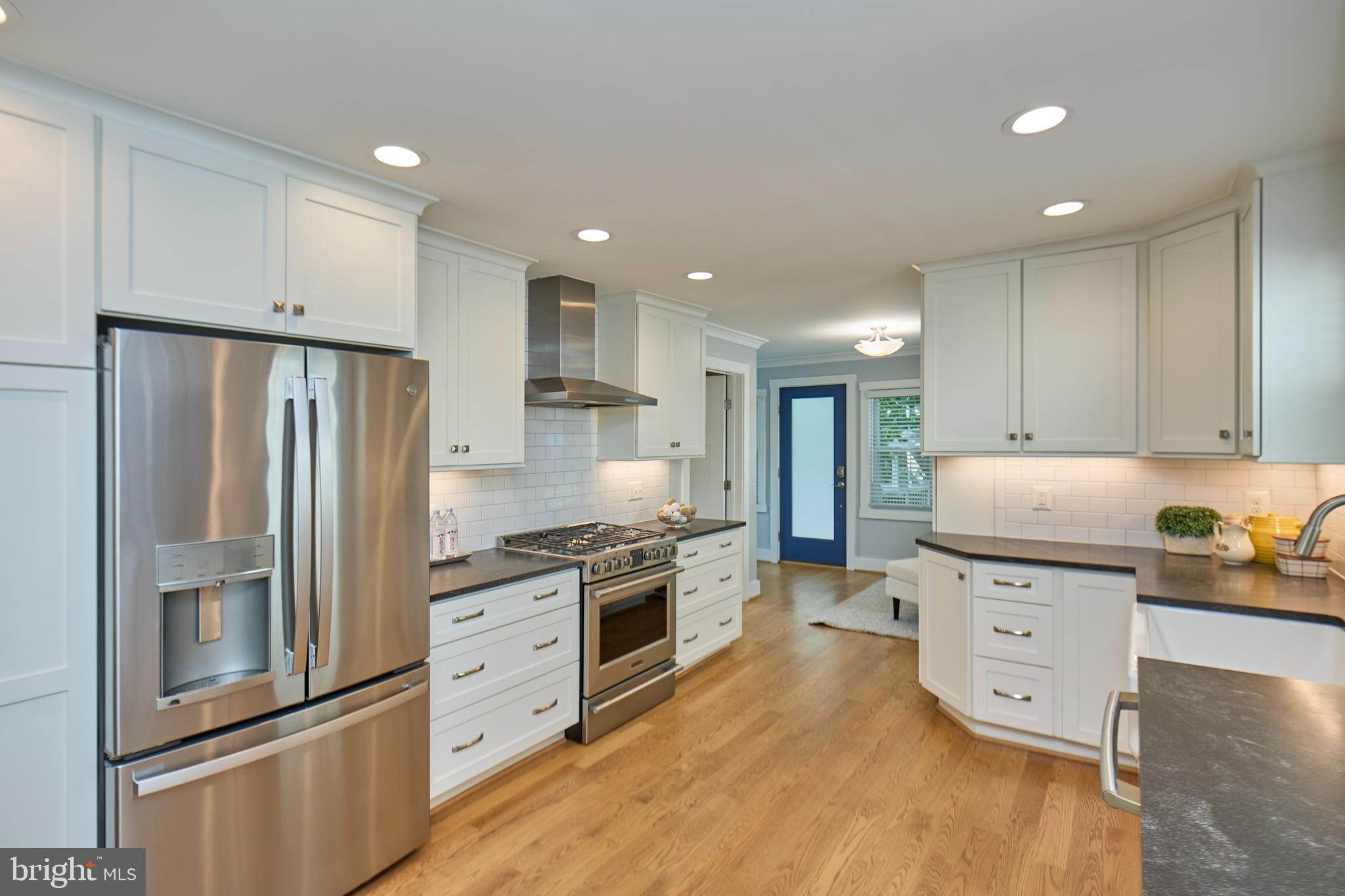 a kitchen with stainless steel appliances granite countertop a refrigerator a stove and a sink