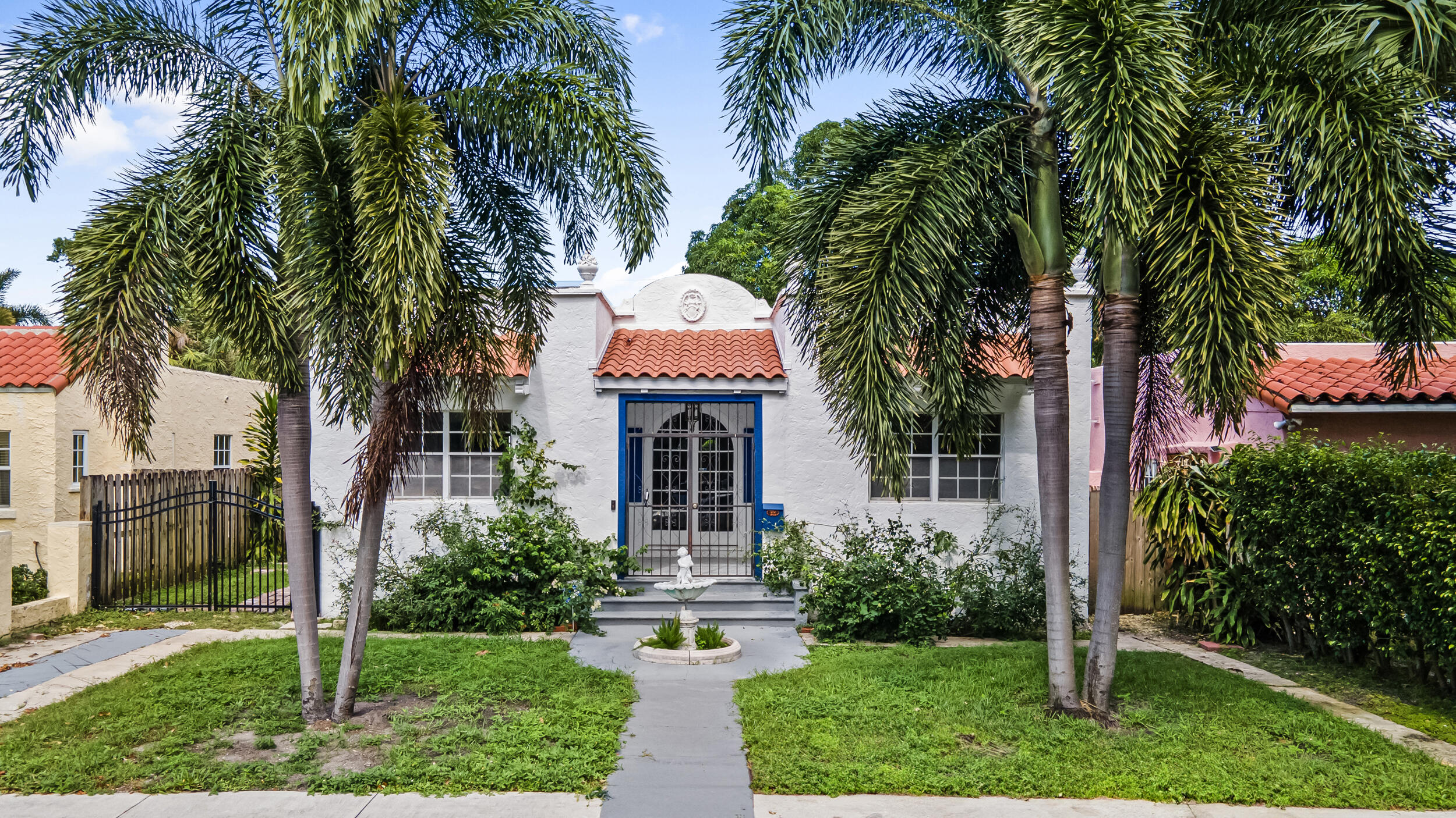 a front view of a house with a yard and palm trees