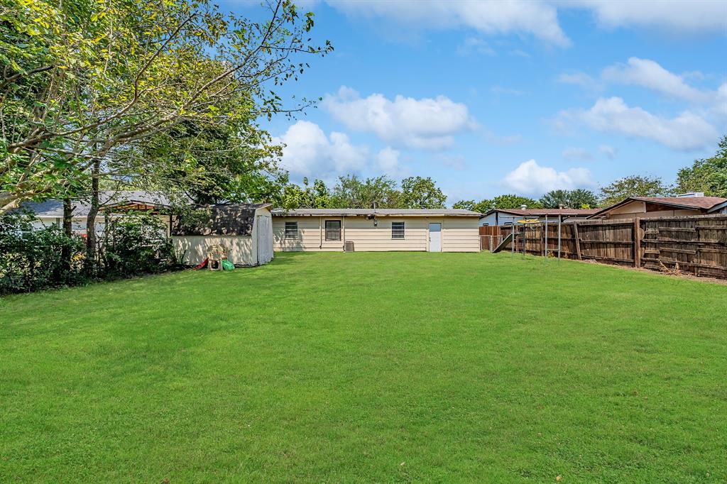 a view of a house with a yard and a large tree