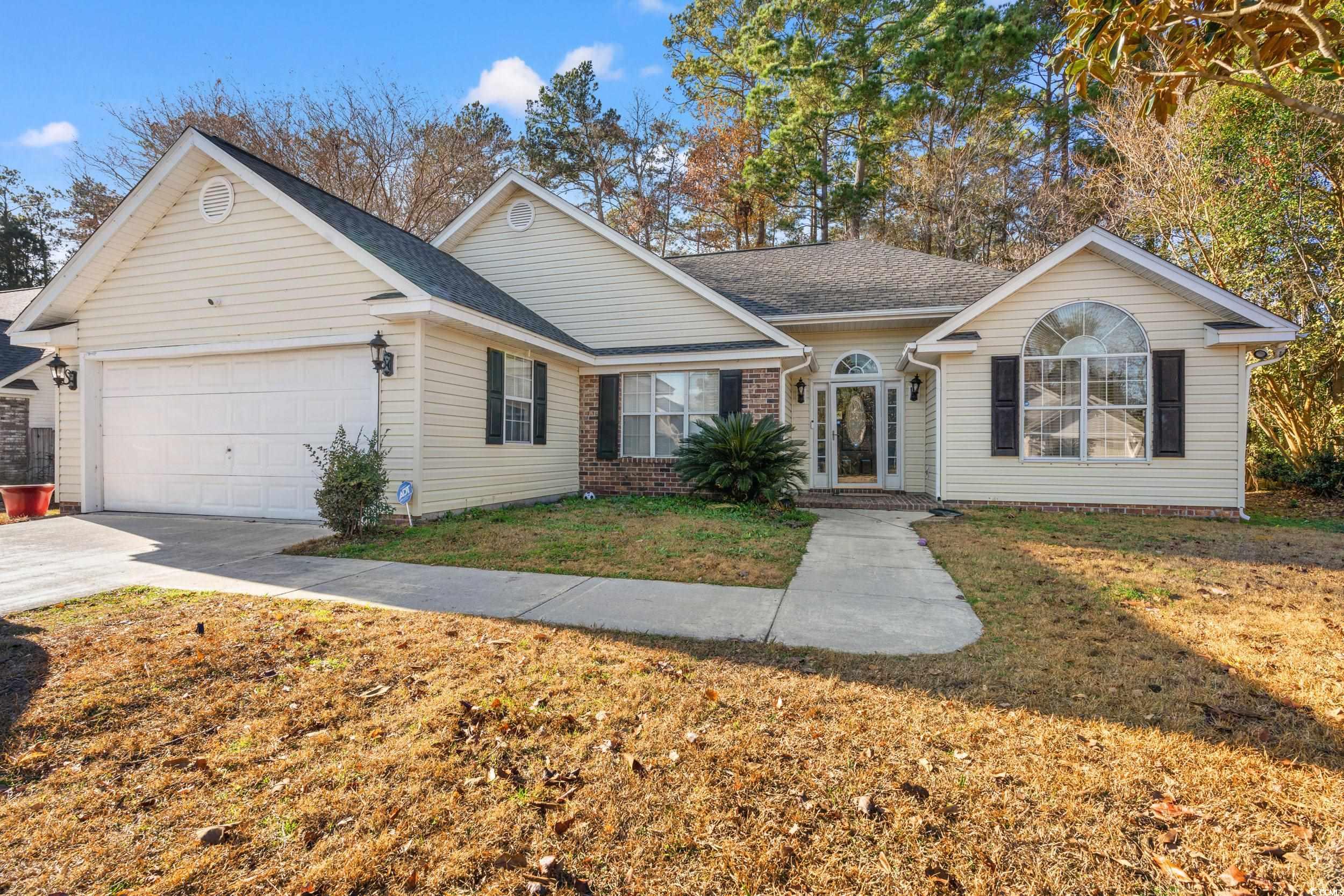 Single story home featuring a front yard and a gar