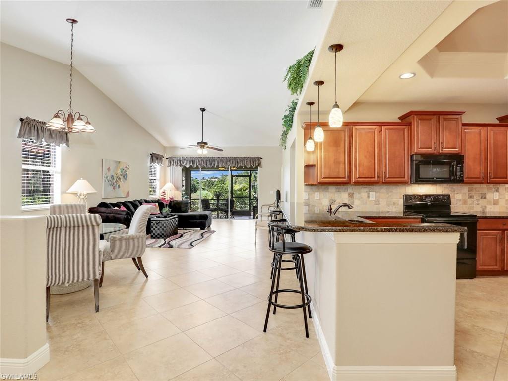 a kitchen with stainless steel appliances kitchen island granite countertop a table chairs in it and a window