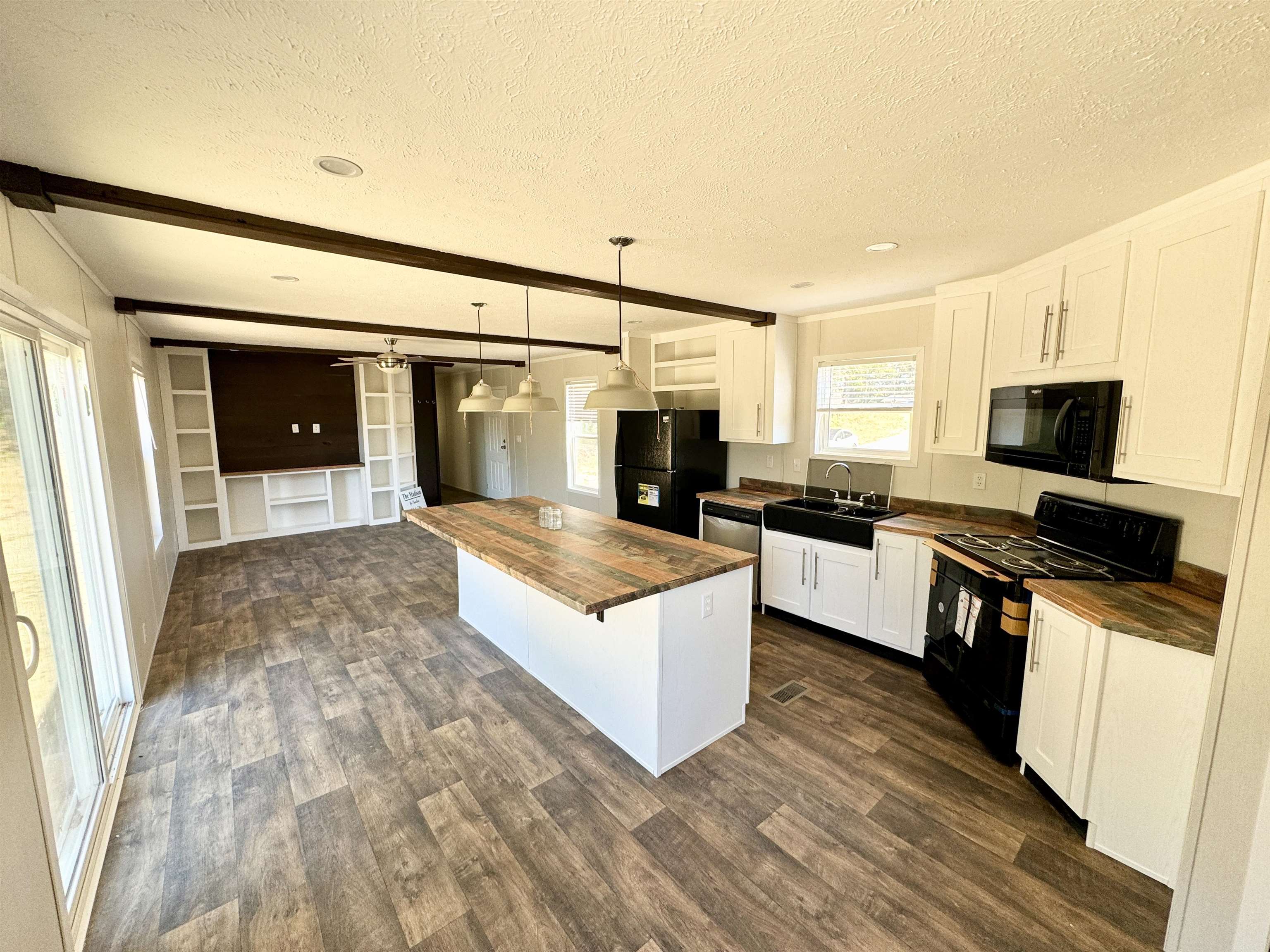 Kitchen with white cabinetry, black appliances, pendant lighting, and butcher block countertops