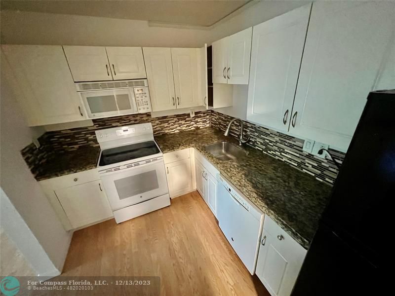 a kitchen with white cabinets and appliances