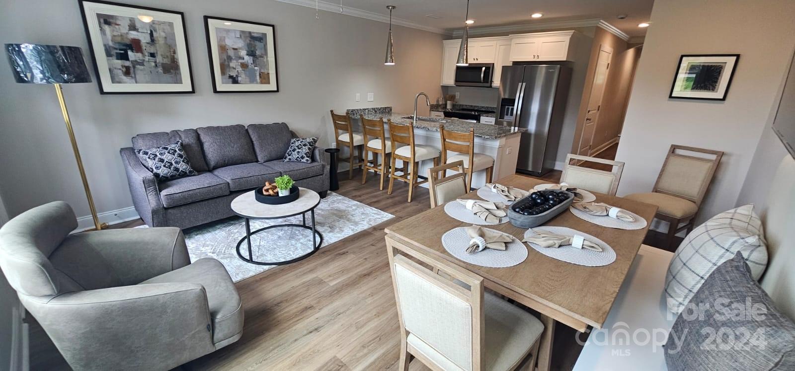 a living room with stainless steel appliances furniture a dining table and chairs