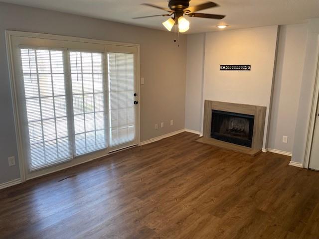 an empty room with wooden floor fireplace fan and windows