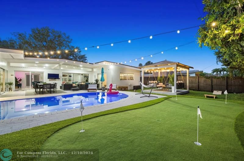 a view of a swimming pool with lawn chairs and a big yard