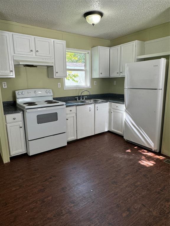 a kitchen with granite countertop white cabinets and white appliances