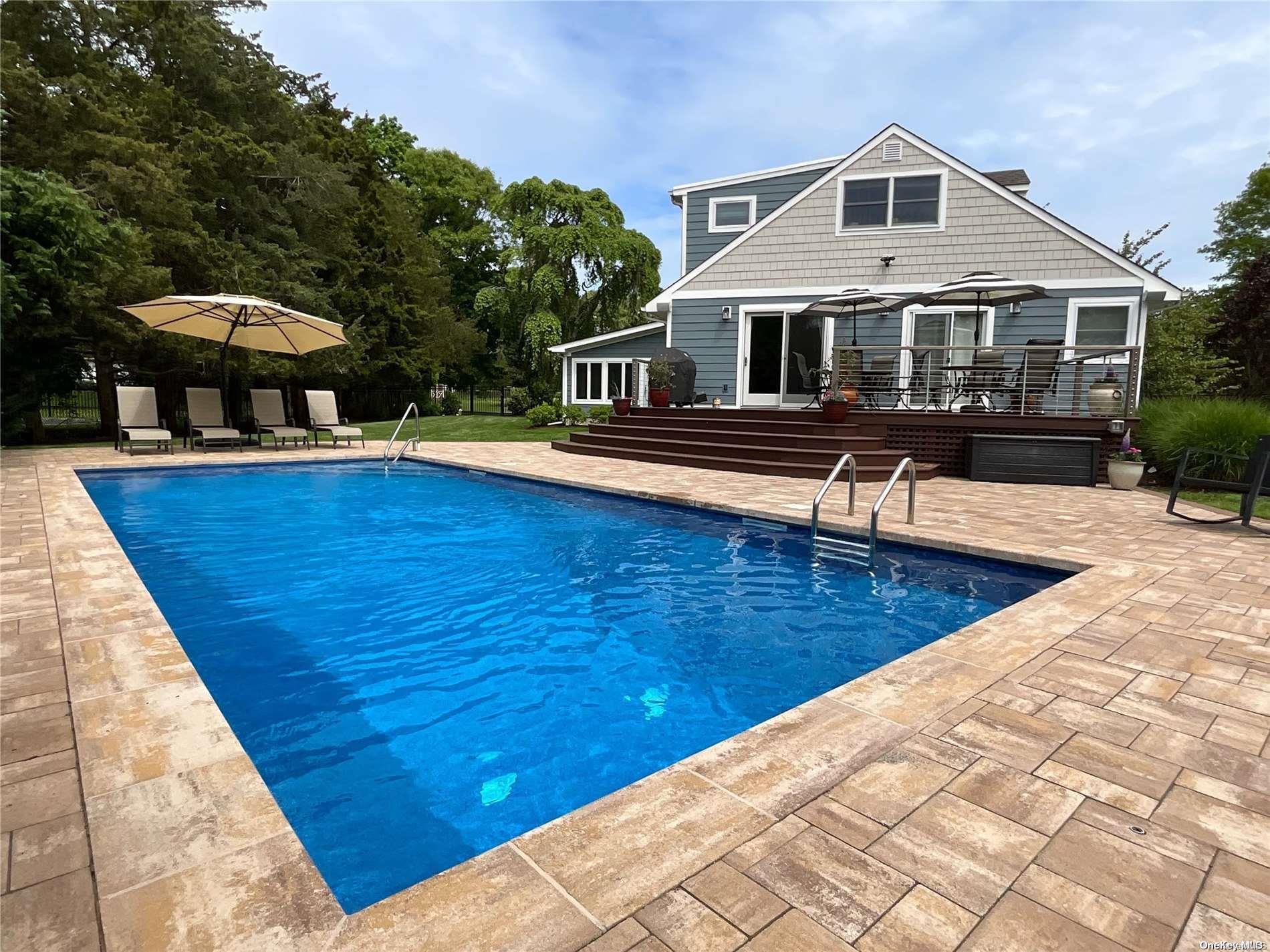 a front view of house with yard swimming pool and chairs