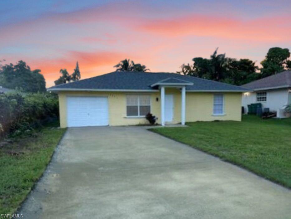 Ranch-style house featuring a garage and lawn