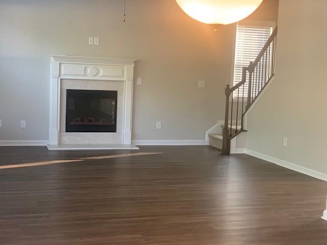 a view of an empty room with wooden floor and a fireplace