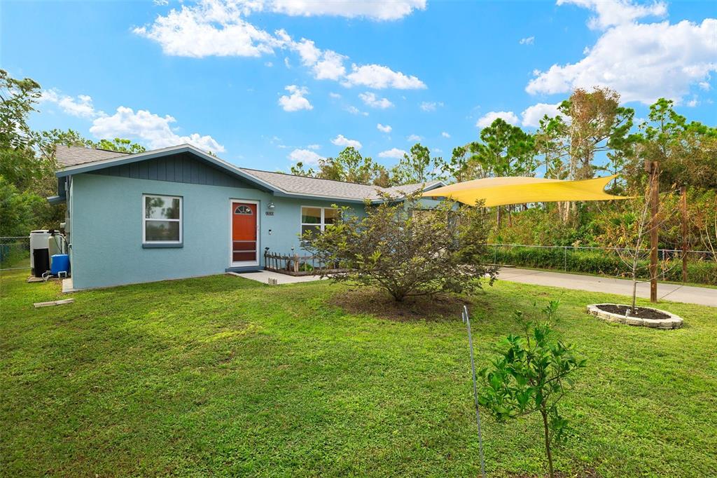 a backyard of a house with table and chairs plants and large tree