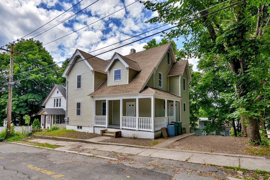 a view of a house with a yard and large tree