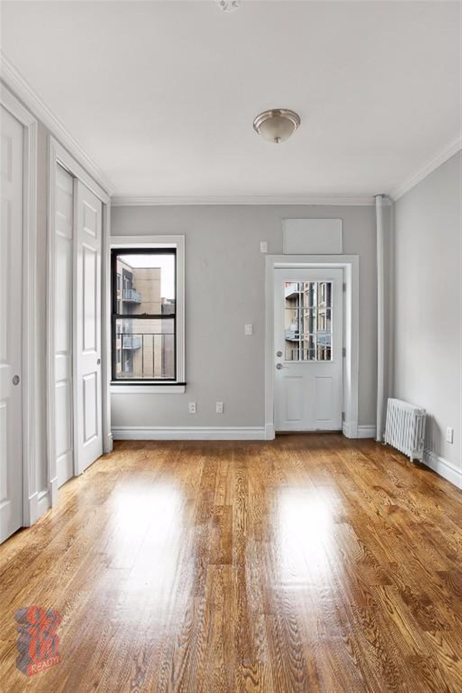 a view of empty room with wooden floor and fan