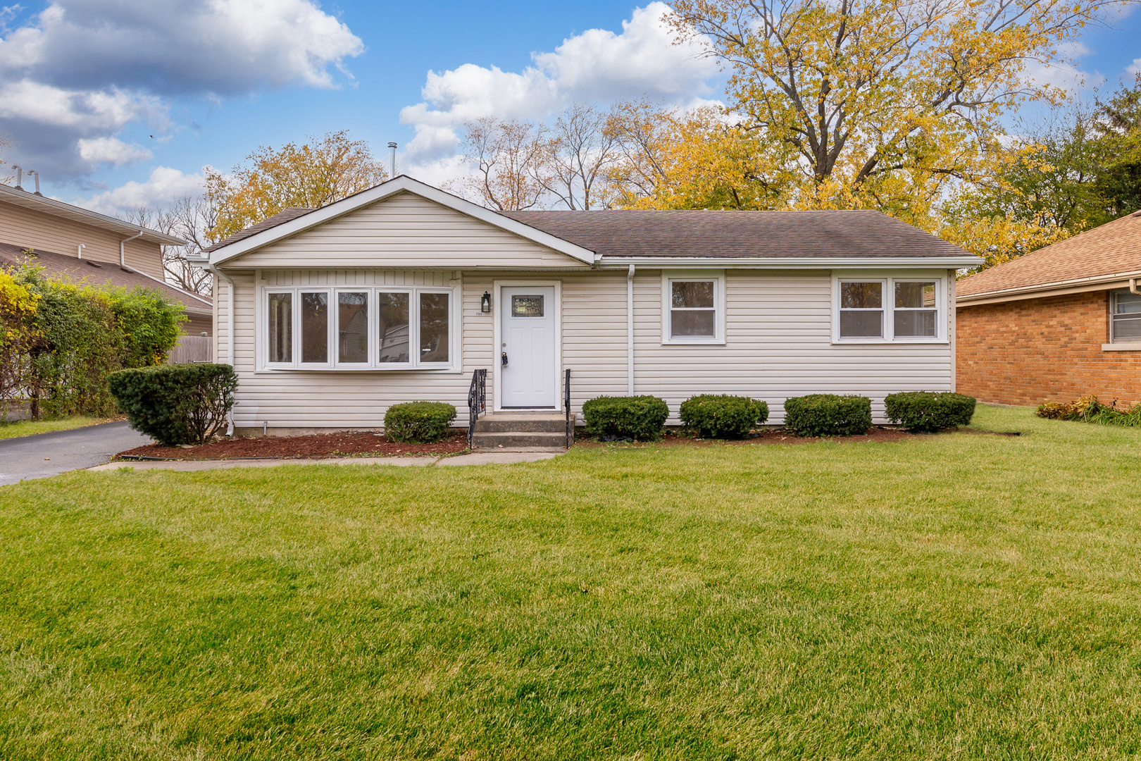 a front view of house with yard and trees in the background