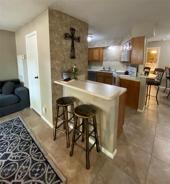 a kitchen with stainless steel appliances kitchen island granite countertop a sink a stove and chairs