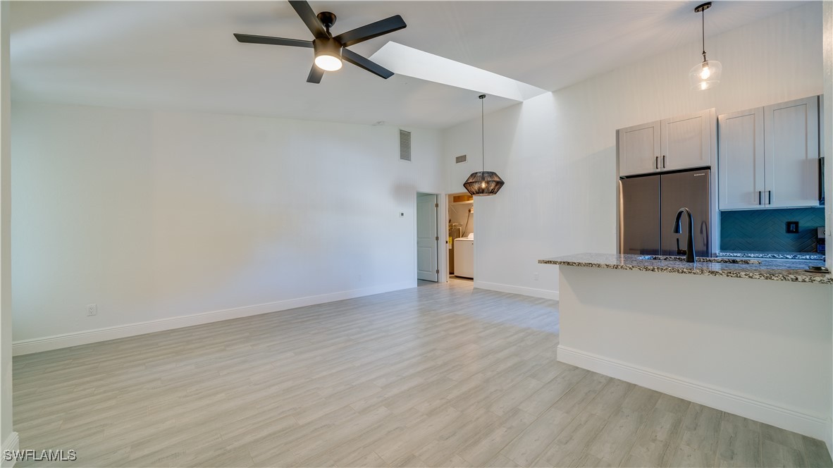 a view of kitchen and empty room with wooden floor