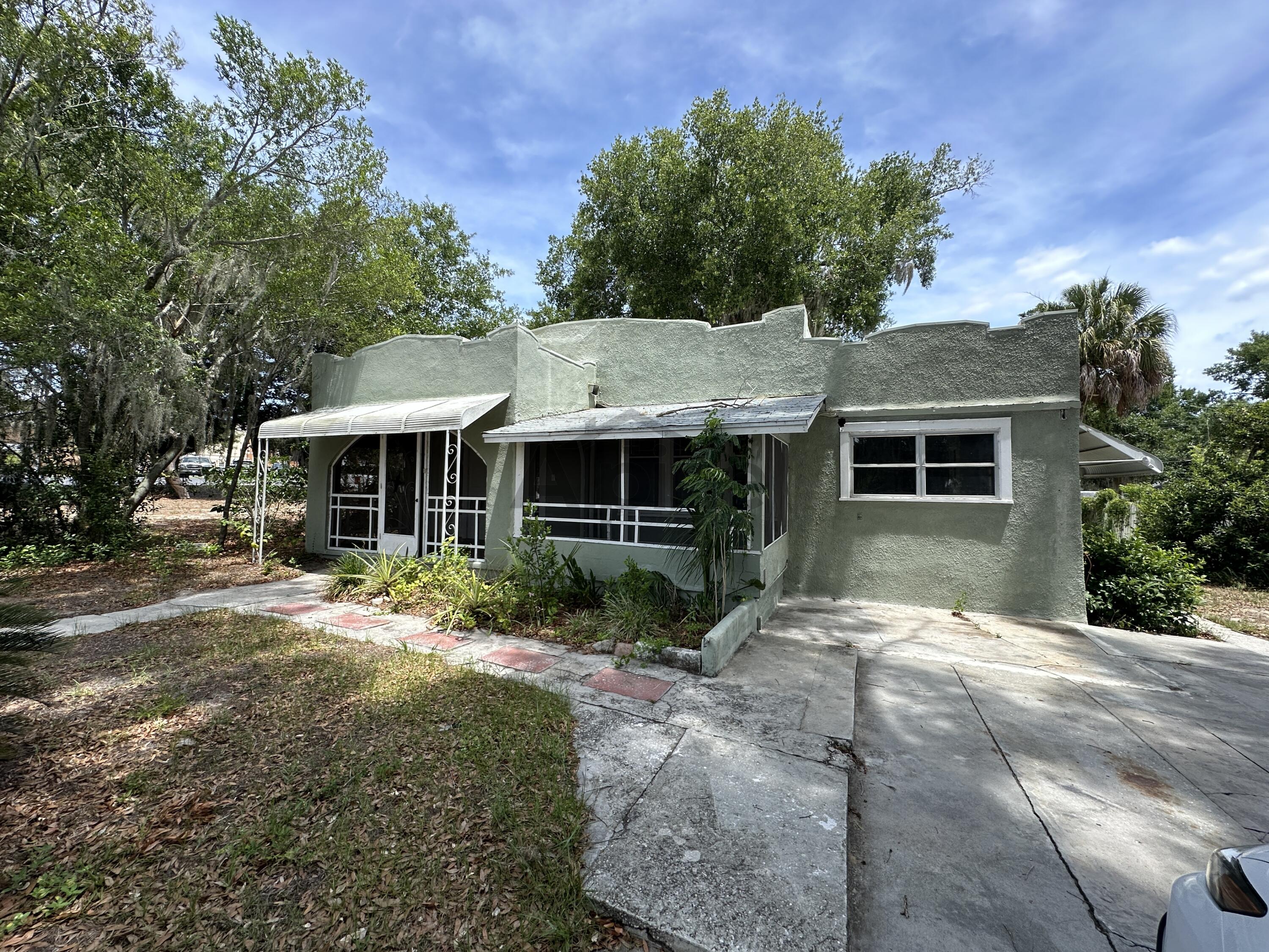 a front view of a house with a garden and trees