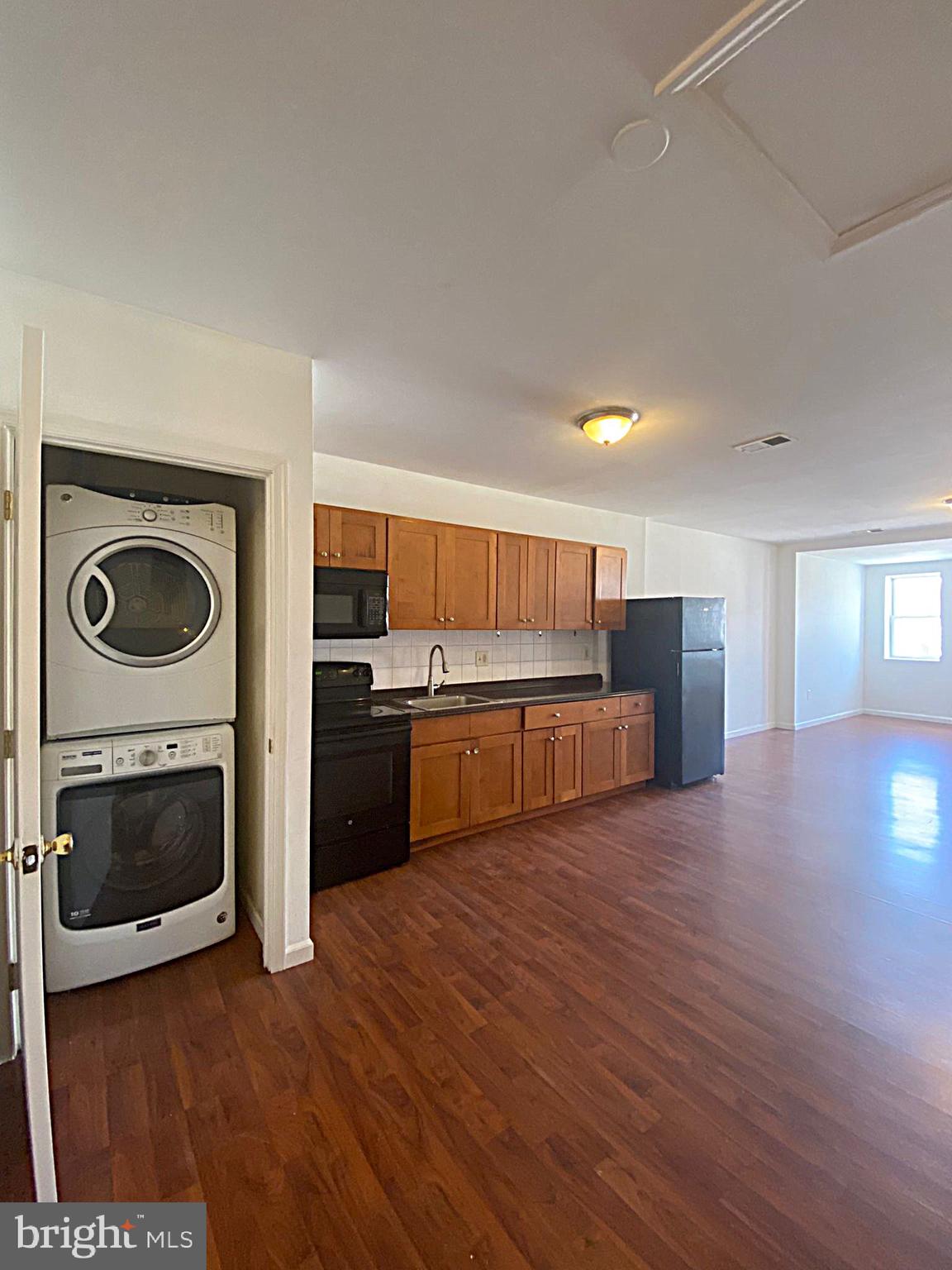 a view of a kitchen with a stove wooden cabinets and entryway