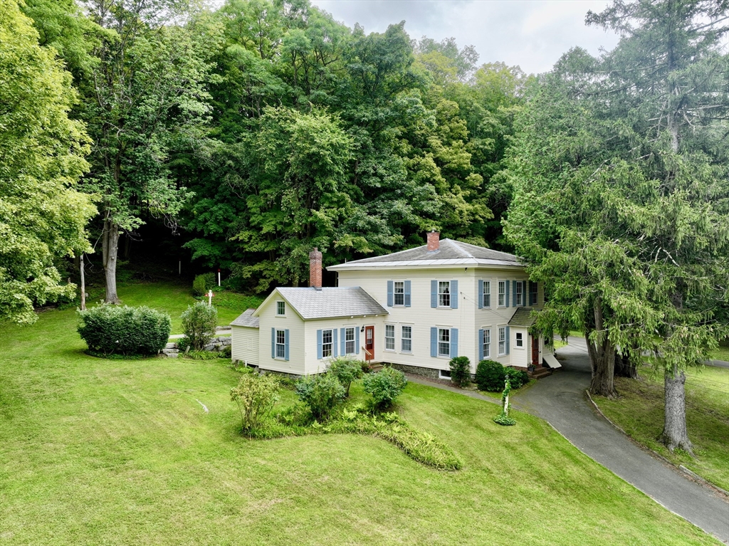 a white house with a big yard and large trees