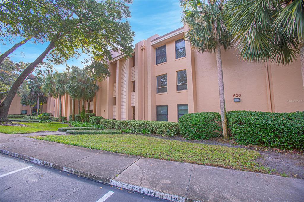 a view of a building with a yard and large trees