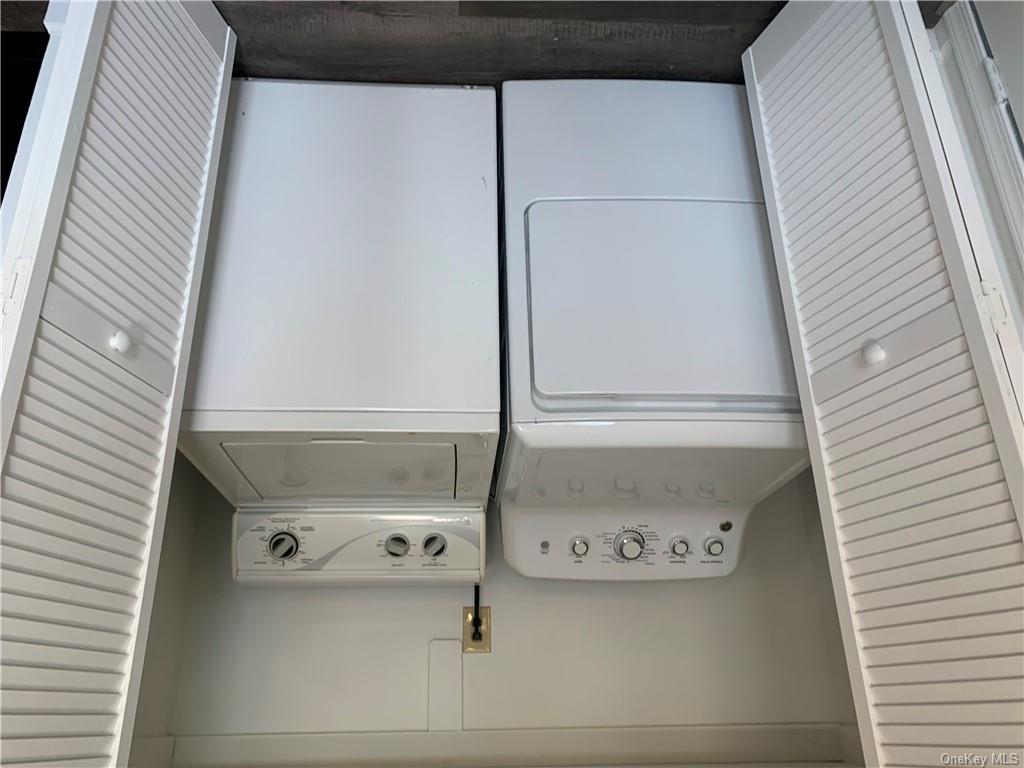 Clothes washing area with dark wood-type flooring and independent washer and dryer