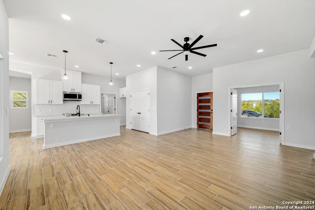 a view of an empty room with kitchen and window