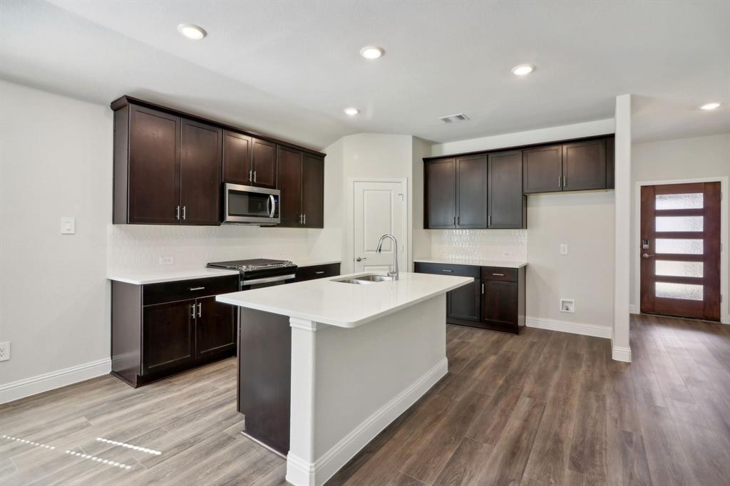 a kitchen with a sink a counter top space stainless steel appliances and cabinets