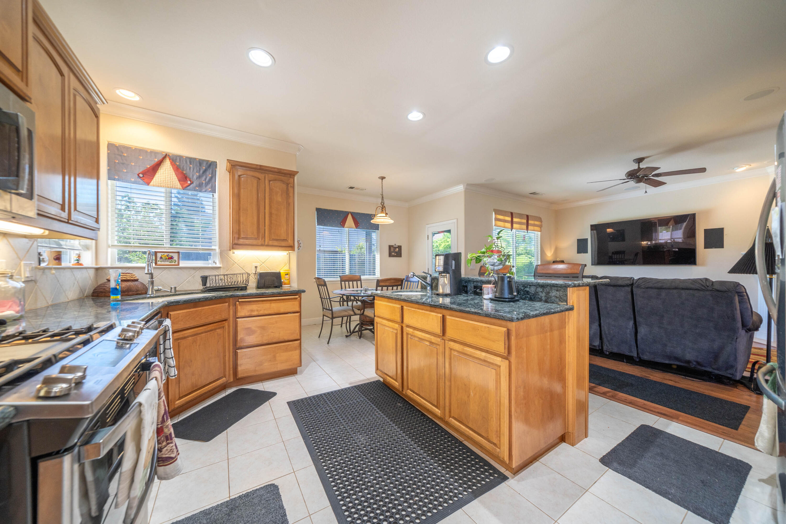 a large kitchen with stainless steel appliances granite countertop a stove top oven a sink dishwasher a dining table and chairs with wooden floor