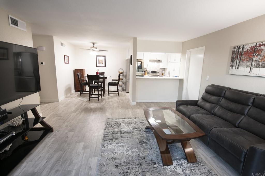 a living room with furniture a table and kitchen view