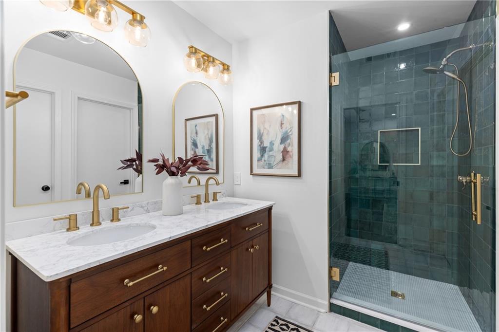 a bathroom with a granite countertop sink a mirror and a shower