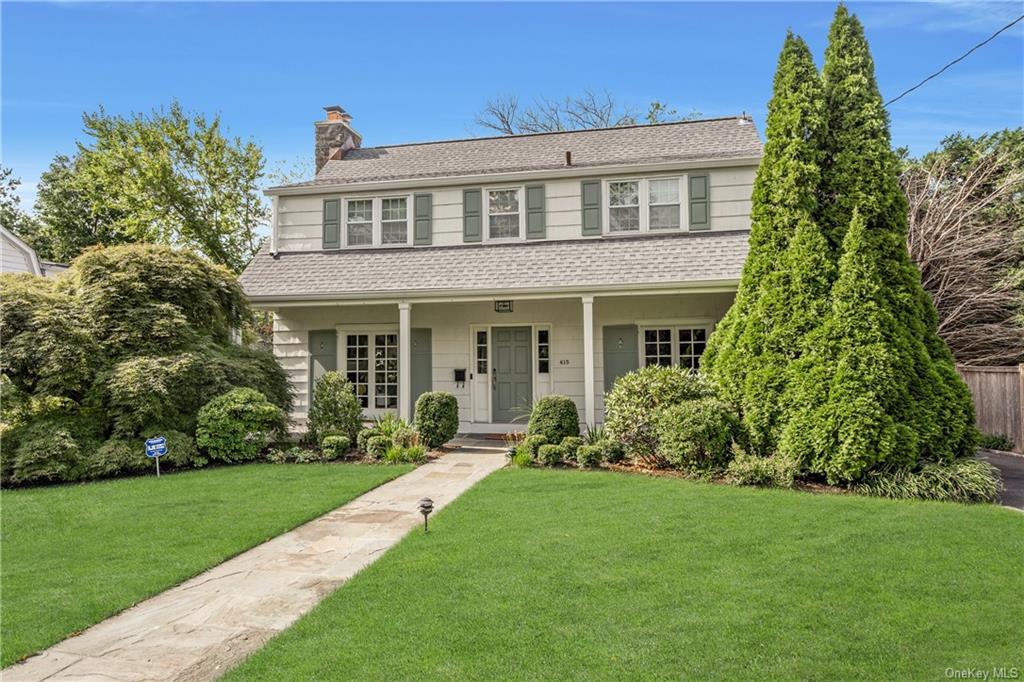 View of front of classic center hall Colonial with lush front lawn