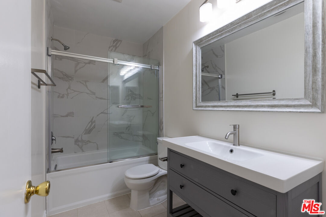 a bathroom with a bathtub shower sink mirror and toilet